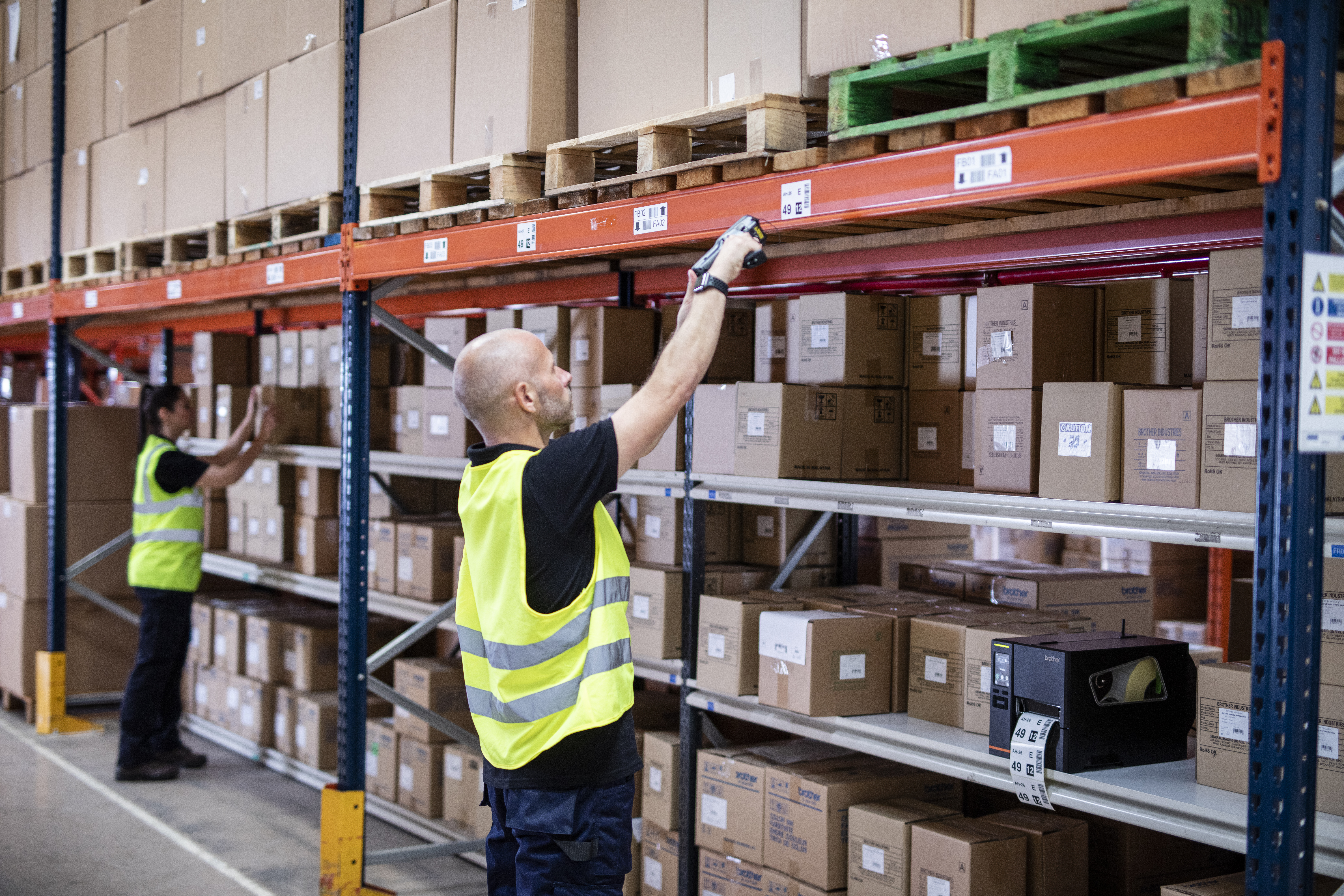 Male warehouse employee scanning barcode on shelving unit